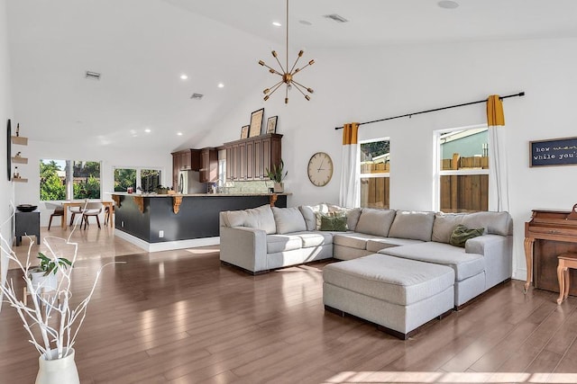 living room with high vaulted ceiling, a notable chandelier, and dark hardwood / wood-style flooring