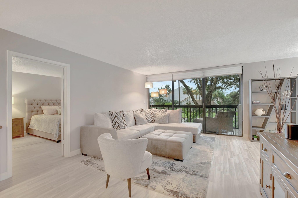 living room featuring light hardwood / wood-style floors, a textured ceiling, and expansive windows