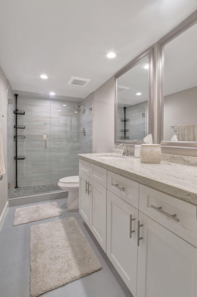 bathroom featuring toilet, vanity, and a shower with shower door