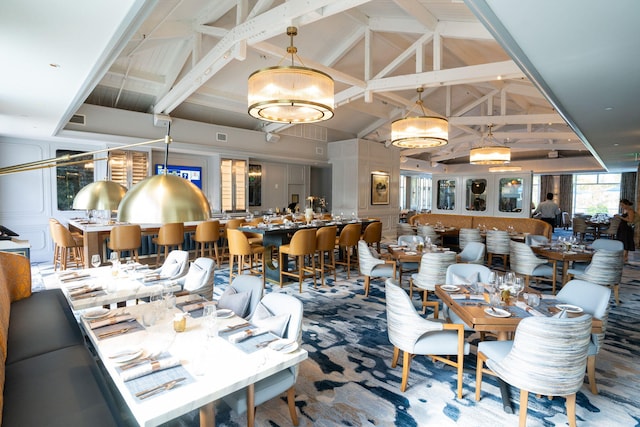 carpeted dining area with high vaulted ceiling and beamed ceiling