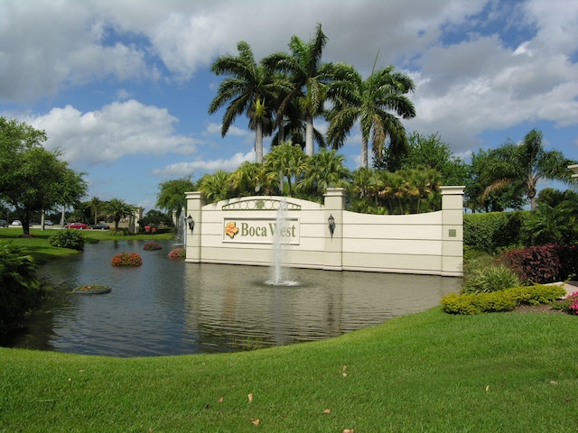 community sign with a lawn and a water view