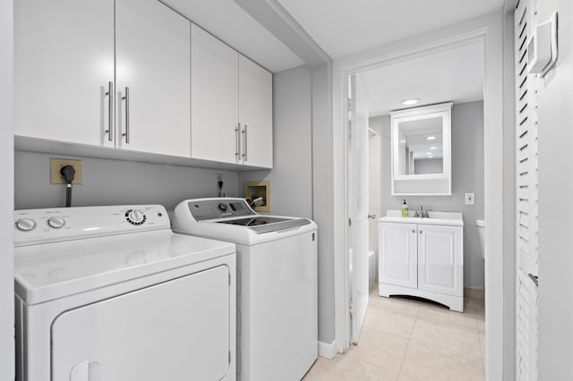 washroom featuring light tile patterned floors, a sink, washing machine and clothes dryer, and cabinet space