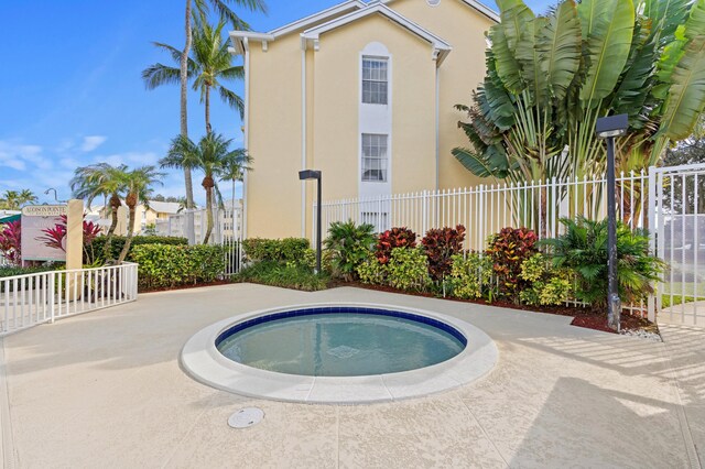 view of pool featuring a patio area, fence, and an in ground hot tub