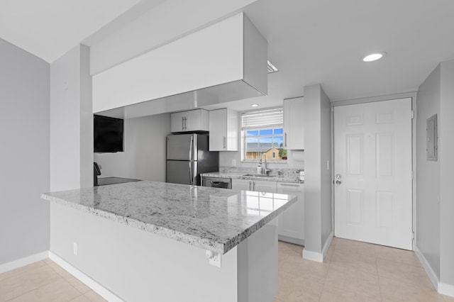 kitchen featuring sink, white cabinetry, stainless steel appliances, light stone countertops, and kitchen peninsula