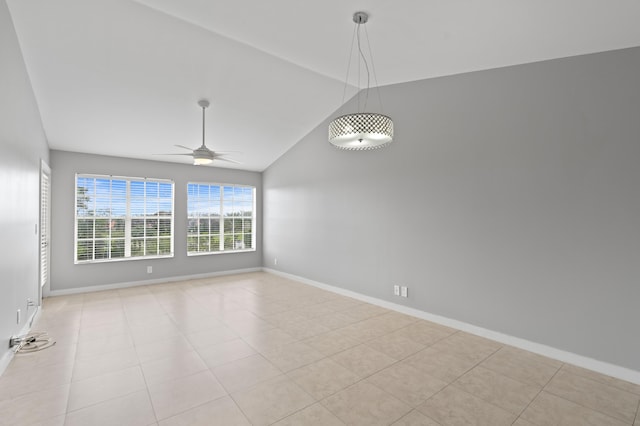 spare room featuring lofted ceiling, light tile patterned floors, baseboards, and a ceiling fan