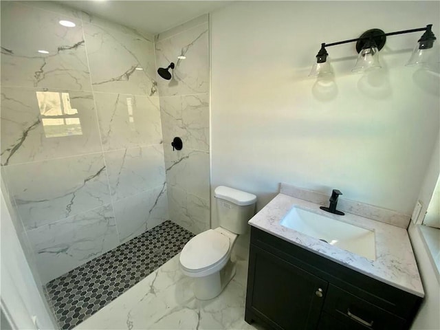 bathroom with tiled shower, vanity, and toilet