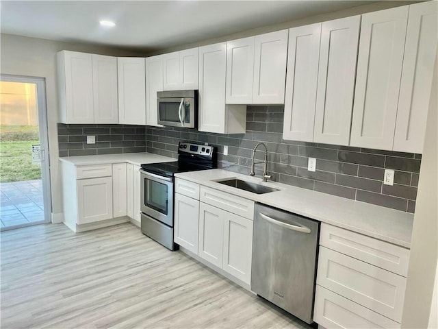 kitchen with white cabinets, backsplash, sink, and stainless steel appliances