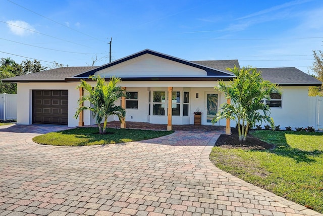 ranch-style home with an attached garage, fence, decorative driveway, stucco siding, and a front yard