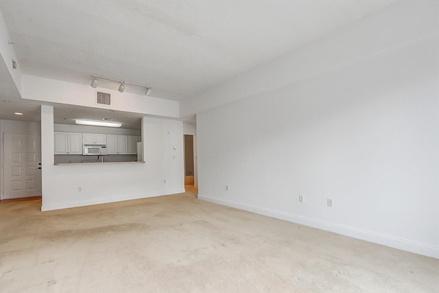 unfurnished living room with track lighting and light carpet