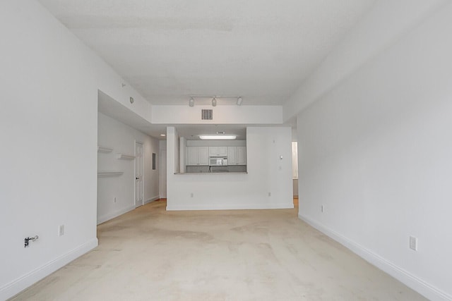 unfurnished living room with light carpet and rail lighting