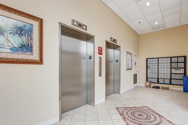 hallway featuring a mail area, light tile patterned floors, and elevator