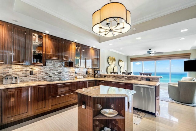 kitchen with decorative backsplash, dishwasher, a kitchen island, ceiling fan with notable chandelier, and sink