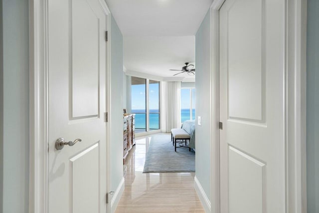 hallway with a wall of windows, light hardwood / wood-style flooring, and a water view