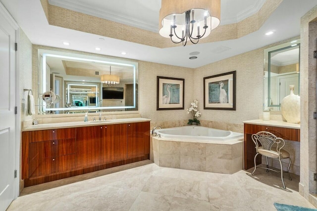 bathroom with tiled tub, a tray ceiling, a notable chandelier, ornamental molding, and vanity