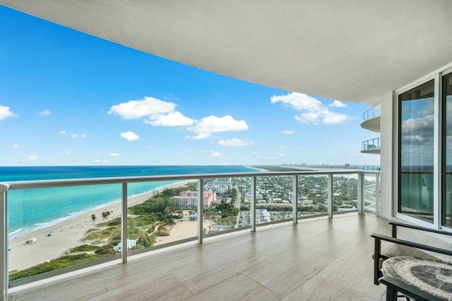 balcony with a water view and a view of the beach