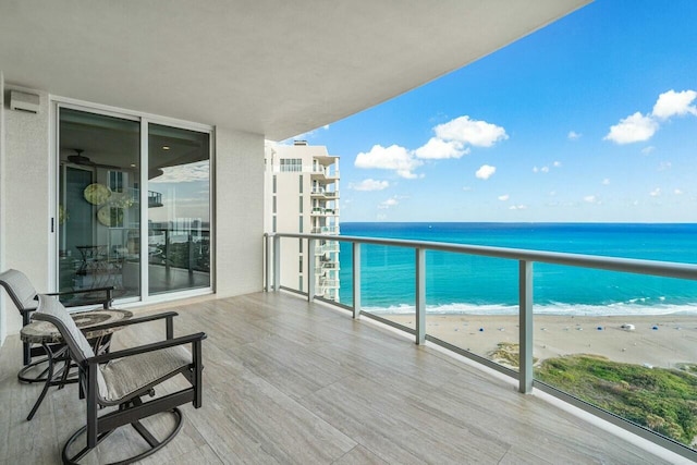 balcony with a water view and a view of the beach