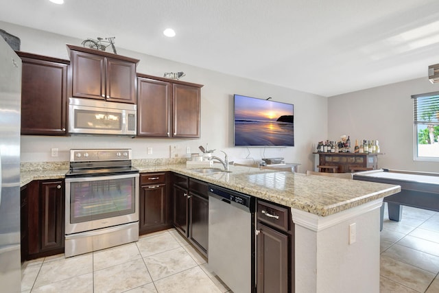 kitchen with light tile patterned floors, appliances with stainless steel finishes, kitchen peninsula, and sink