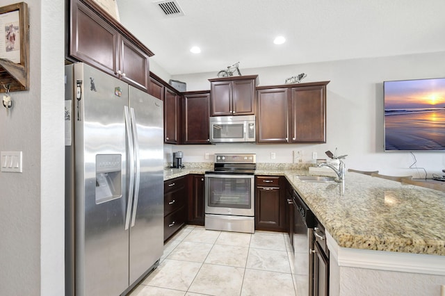 kitchen featuring light tile patterned floors, kitchen peninsula, stainless steel appliances, light stone countertops, and sink