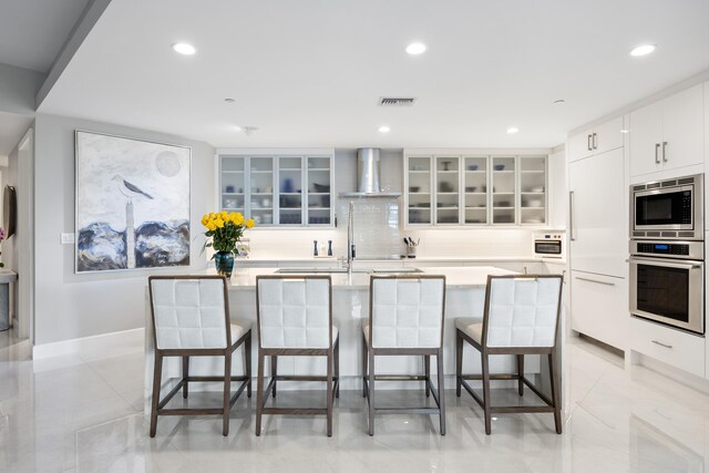 kitchen with white cabinets, a kitchen island with sink, light stone countertops, and sink