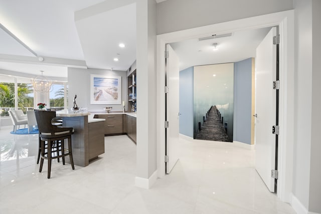 kitchen featuring a kitchen breakfast bar, light tile patterned floors, a chandelier, and a center island