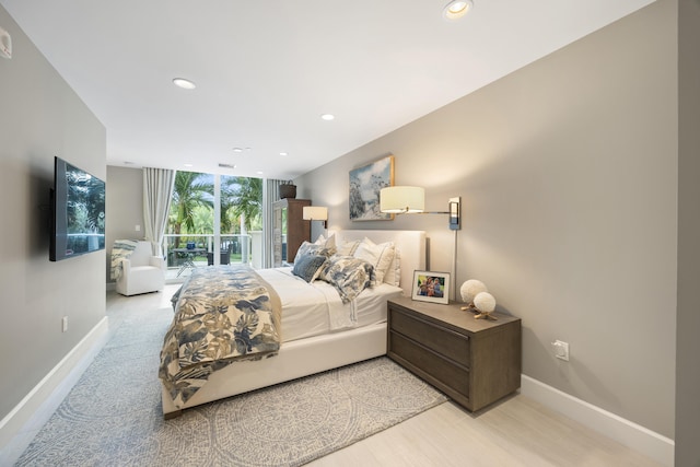 bedroom featuring expansive windows, access to exterior, and light hardwood / wood-style floors