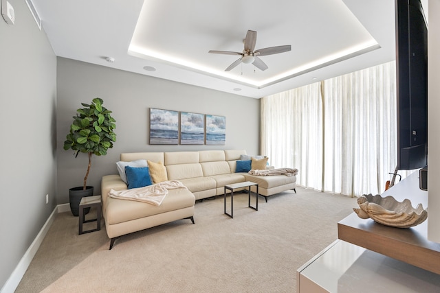 carpeted living room featuring ceiling fan and a tray ceiling