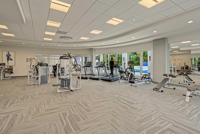 exercise room with light colored carpet and a paneled ceiling