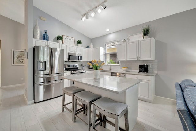 kitchen featuring a breakfast bar area, stainless steel appliances, white cabinets, and a kitchen island