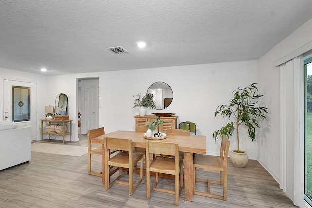 dining room with light hardwood / wood-style floors and a textured ceiling