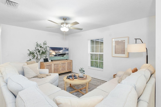 living room featuring ceiling fan and a textured ceiling