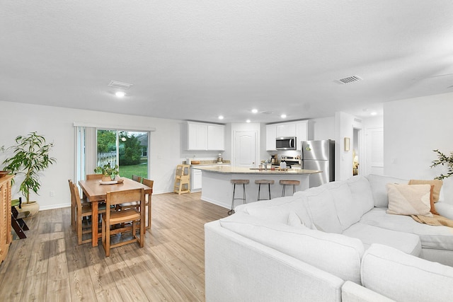 living room with light wood-type flooring and a textured ceiling