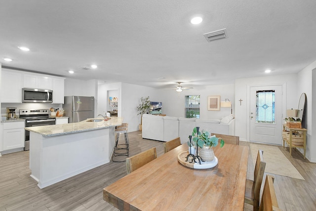 dining space with light hardwood / wood-style floors, sink, a wealth of natural light, and ceiling fan