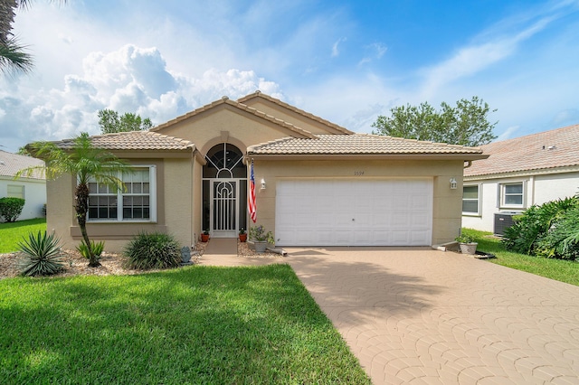 mediterranean / spanish home featuring a front lawn, cooling unit, and a garage