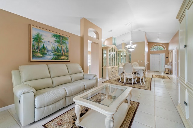 living room with lofted ceiling, light tile patterned floors, and a notable chandelier