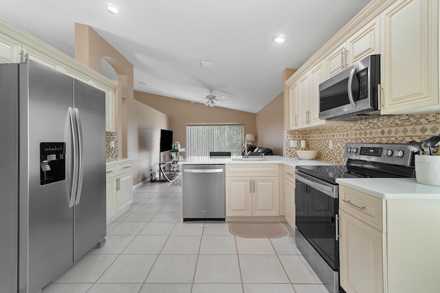 kitchen featuring kitchen peninsula, ceiling fan, appliances with stainless steel finishes, decorative backsplash, and vaulted ceiling