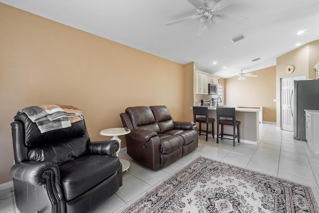 living room with ceiling fan, lofted ceiling, and light tile patterned flooring