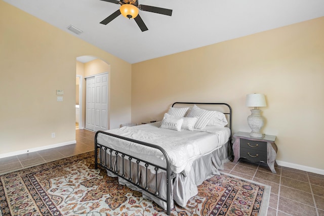 tiled bedroom with ceiling fan and a closet