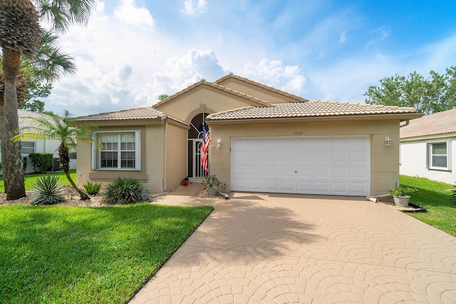 mediterranean / spanish home featuring a front yard and a garage