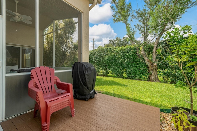 wooden terrace with ceiling fan and a lawn