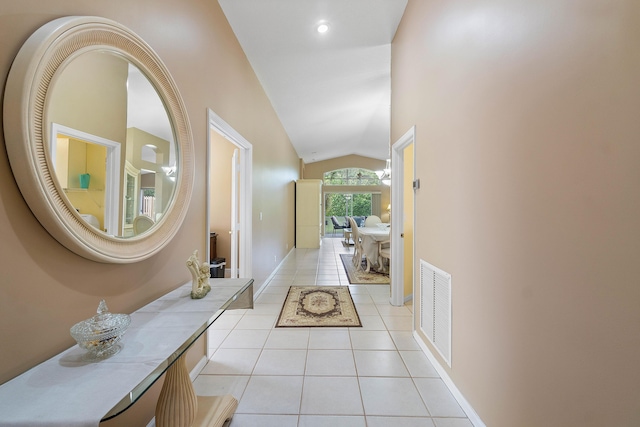 corridor with light tile patterned floors and lofted ceiling