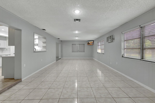 spare room with a textured ceiling and light tile patterned flooring