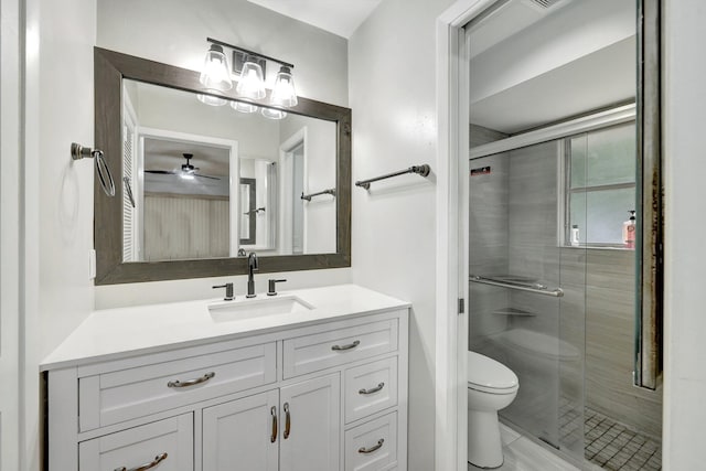 bathroom with toilet, vanity, ceiling fan, and a shower with door