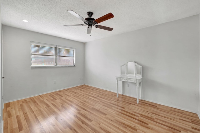 empty room with light wood-type flooring, ceiling fan, and a textured ceiling