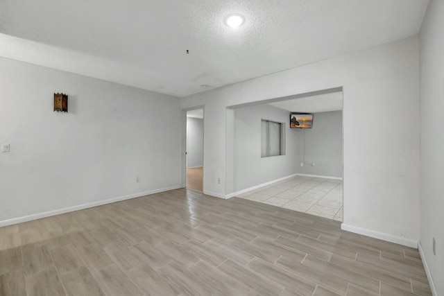 spare room with a textured ceiling and light hardwood / wood-style floors