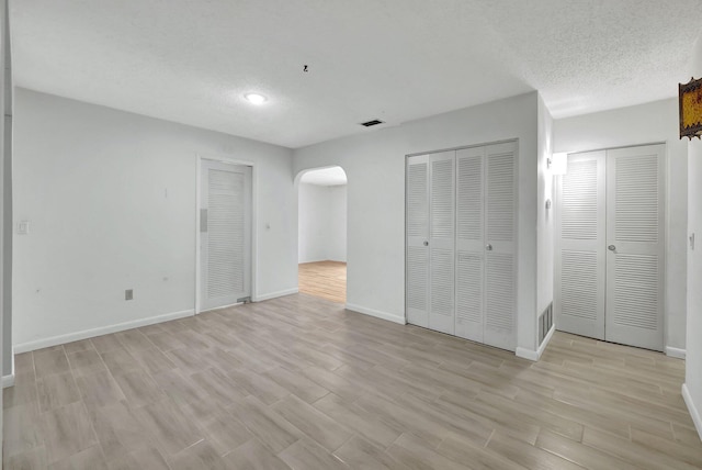 unfurnished bedroom with multiple closets and light hardwood / wood-style floors