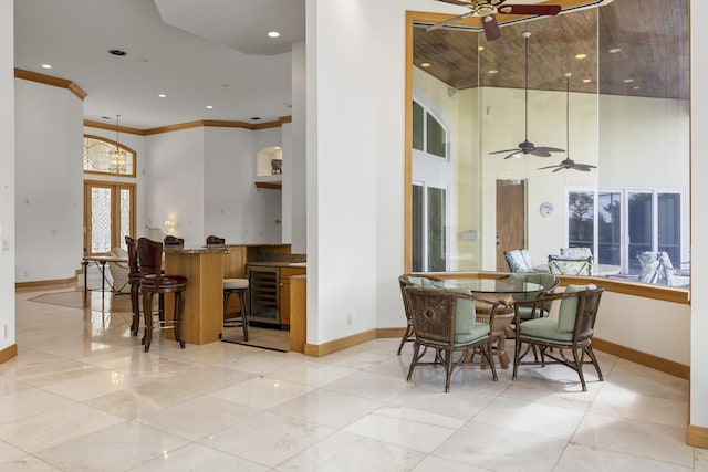 dining area featuring crown molding, ceiling fan with notable chandelier, beverage cooler, and french doors