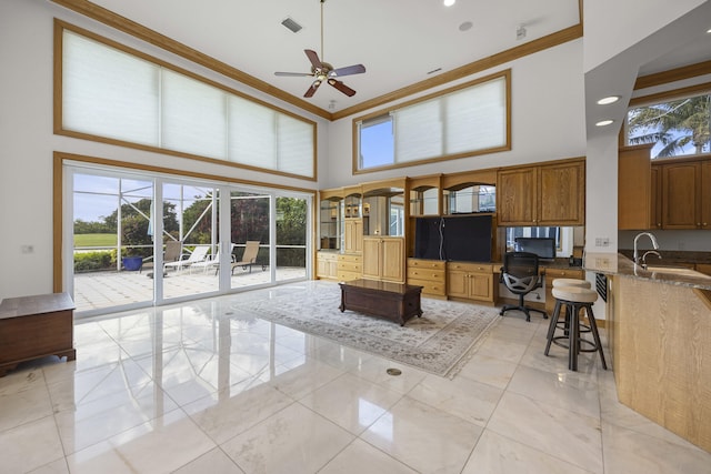 living room with sink, ornamental molding, ceiling fan, and a high ceiling