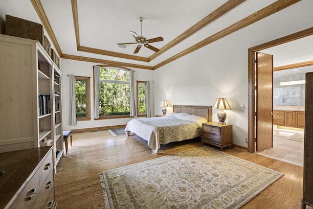 bedroom featuring ensuite bathroom, ornamental molding, ceiling fan, a tray ceiling, and light hardwood / wood-style floors