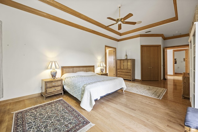 bedroom with crown molding, ceiling fan, a raised ceiling, and hardwood / wood-style floors