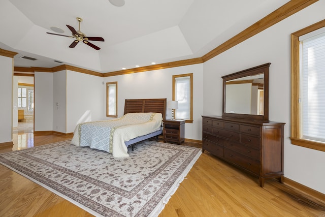 bedroom with crown molding, ceiling fan, a tray ceiling, and light hardwood / wood-style floors